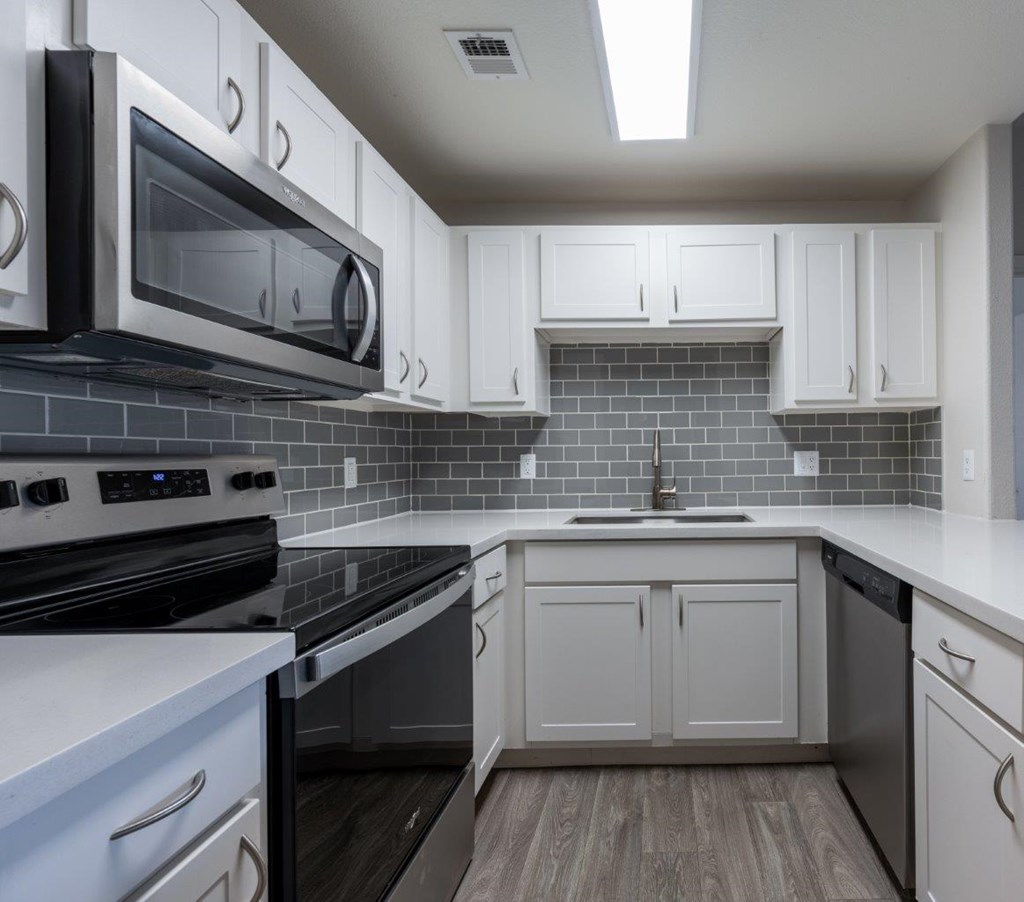 A kitchen with white cabinets and black appliances.