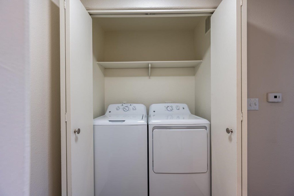 Two white washing machines in a small laundry room.