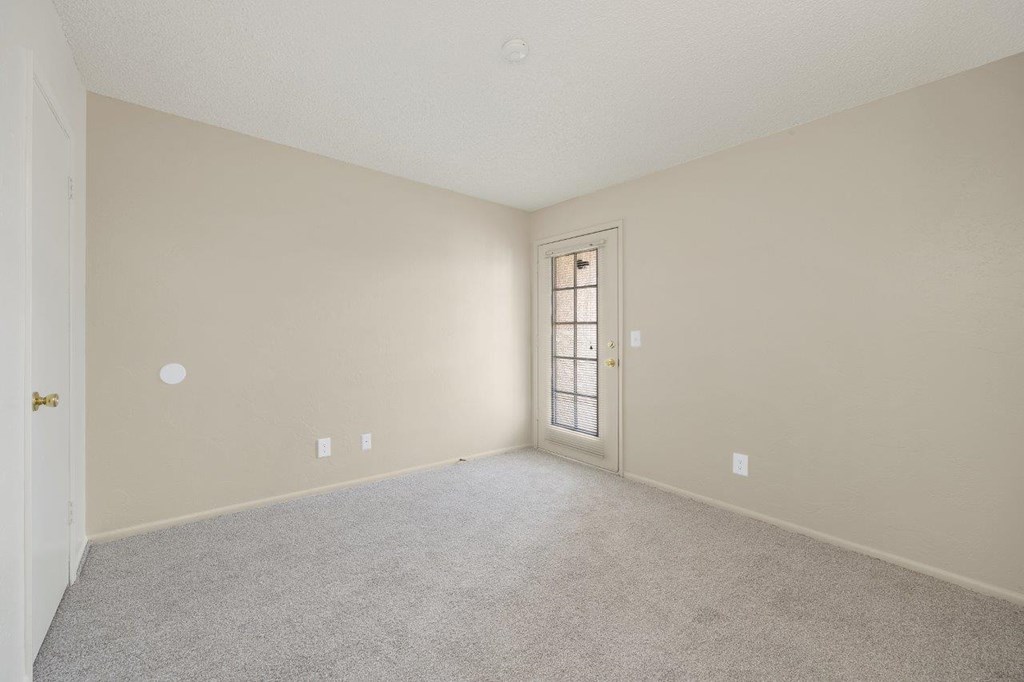 A room with a carpeted floor and a door.