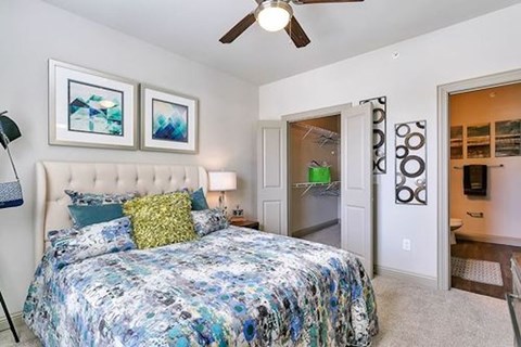 A bedroom with a large bed and a ceiling fan.