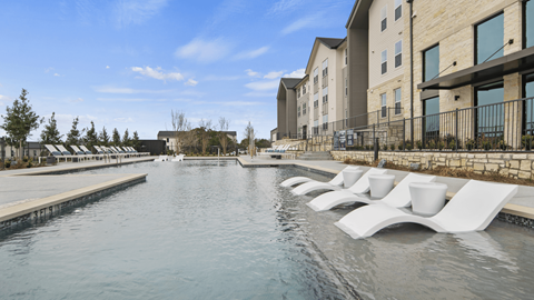 A pool with white chairs and a building in the background.