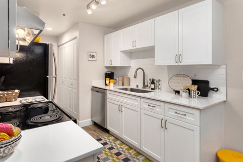 A kitchen with white cabinets and a black refrigerator.
