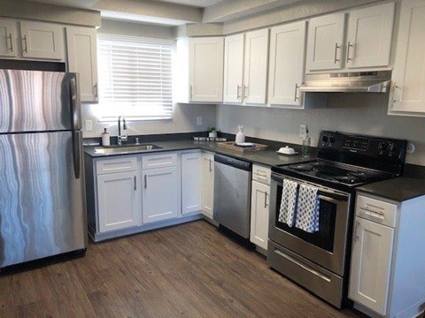 A kitchen with white cabinets and a black refrigerator.