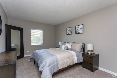 A bedroom with a bed, nightstand, and two pictures on the wall.