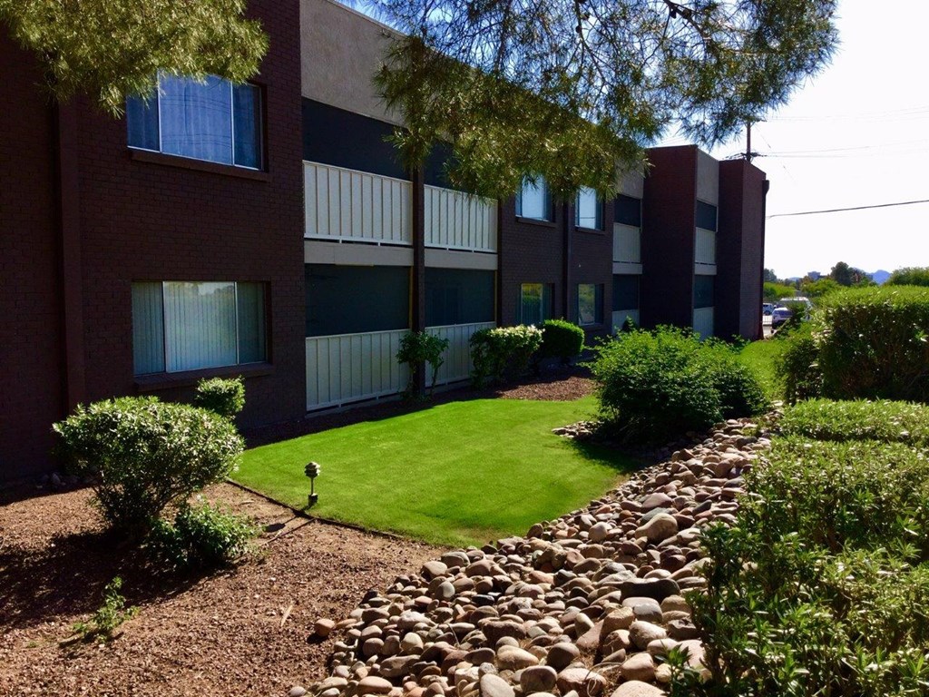 A building with a red brick exterior and a green lawn in front.