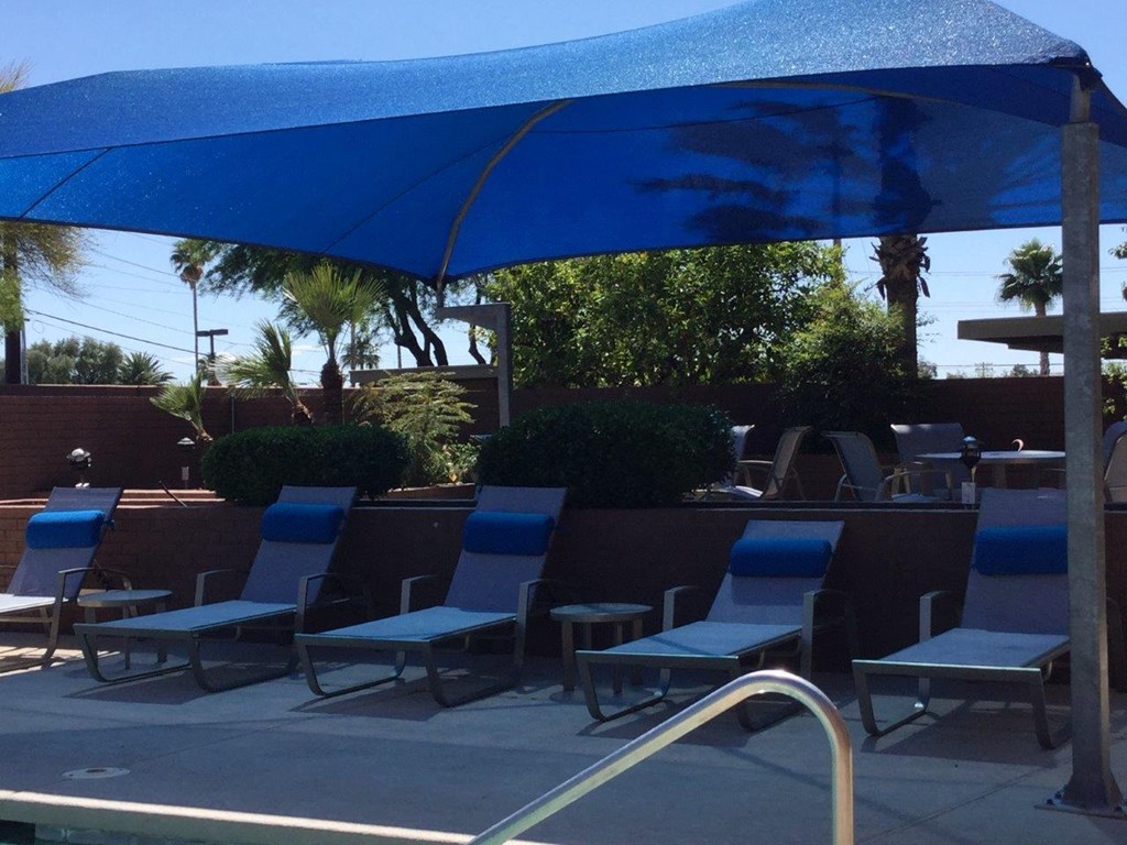 A pool area with blue chairs and a blue umbrella.