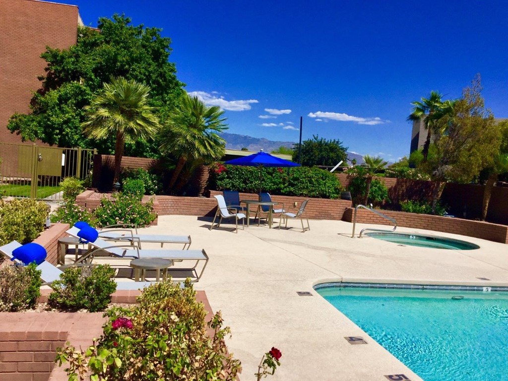 A pool surrounded by chairs and plants.