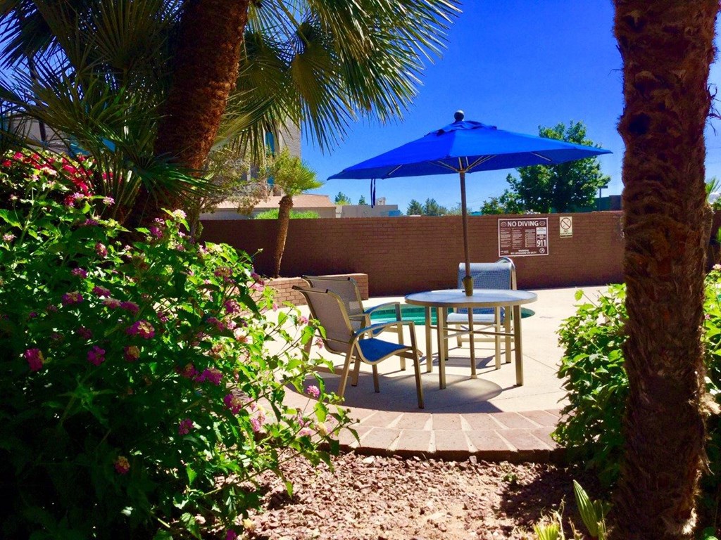 A blue umbrella is over a table with chairs.
