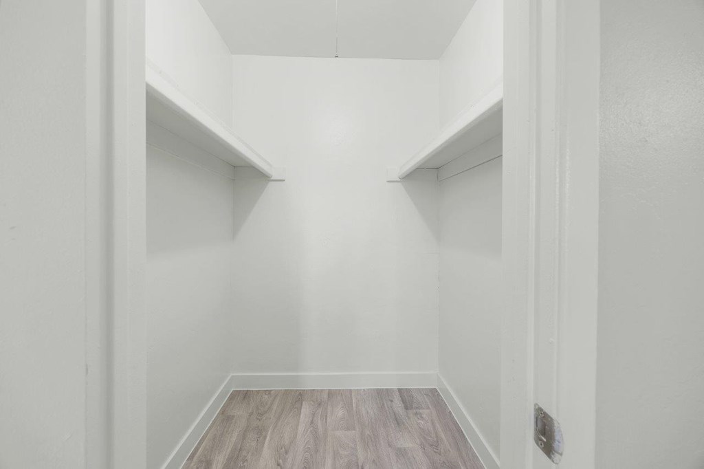 A long hallway with wood floors and white walls.