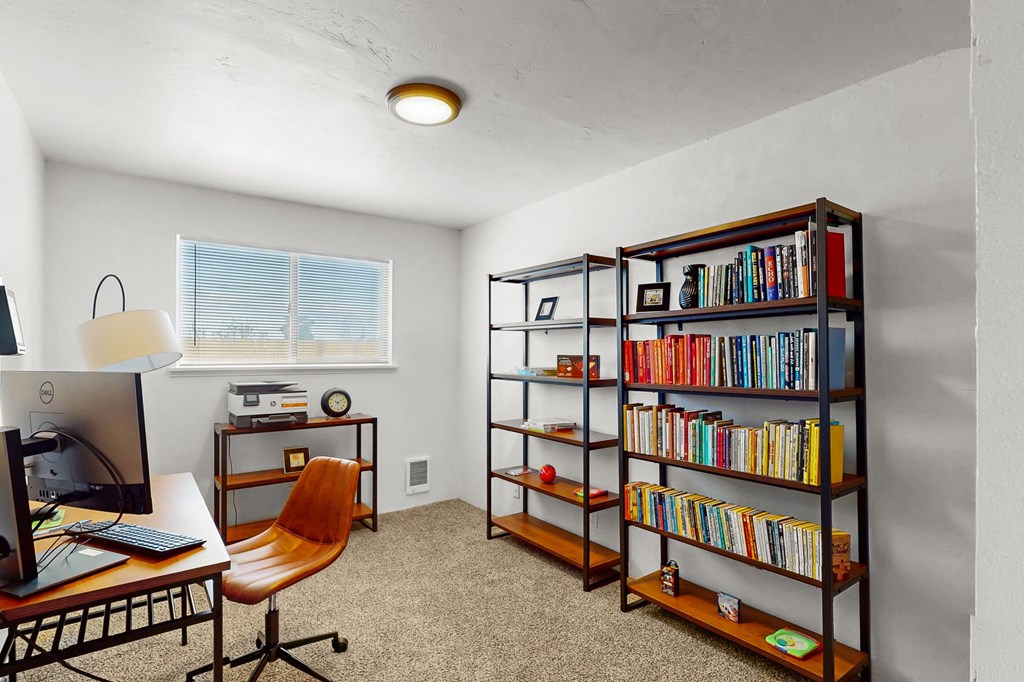 Creekside Apartments a clubhouse office with a bookshelf and a desk with a computer