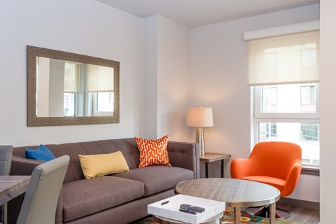 A living room with a grey couch, orange chair, and a coffee table.