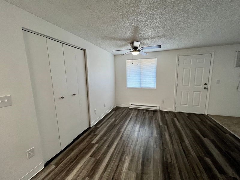 an empty living room with wood floors and a ceiling fan