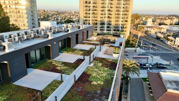 A modern building with a green roof and a parking lot in front.