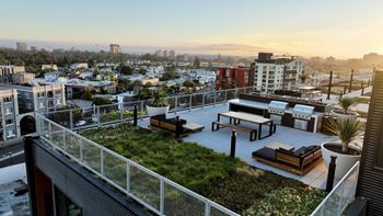 A rooftop patio with a green lawn and seating area overlooking a cityscape.
