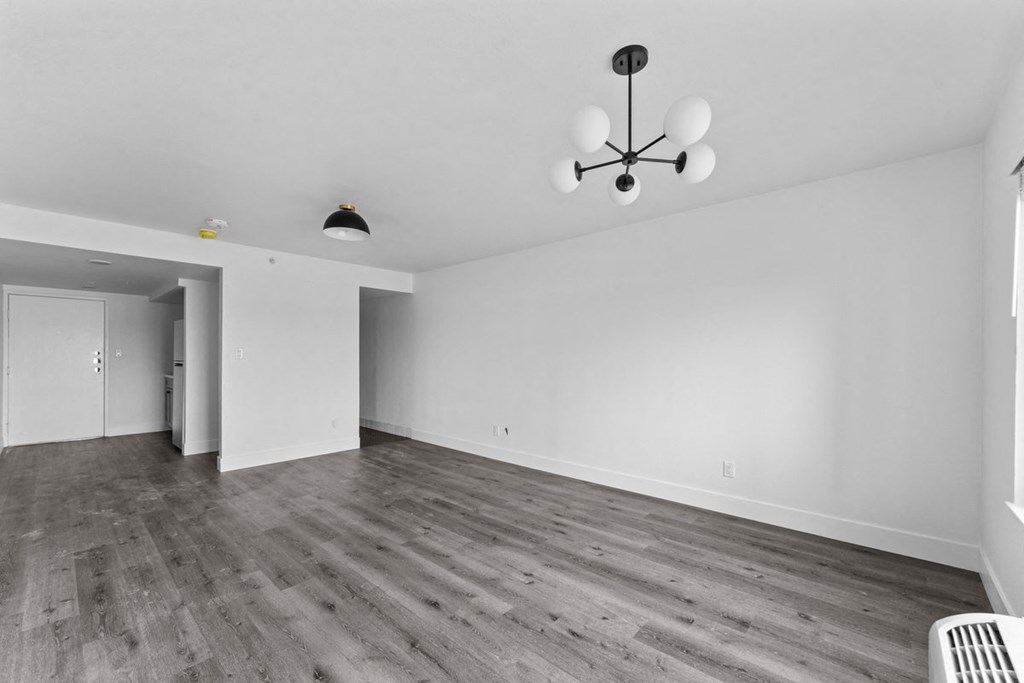 an empty living room with white walls and wood floors
