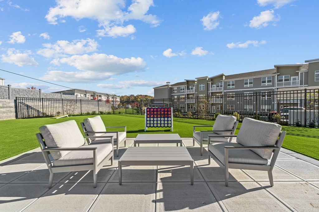 a patio with chairs and a table and a lawn