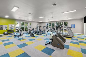 A gym with a variety of equipment including treadmills, weights, and exercise machines.