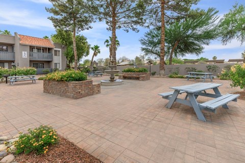 A courtyard with a picnic table and apartment buildings in the background.