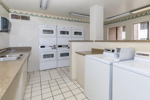 A kitchen with white appliances and a tile floor.