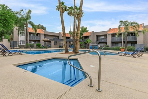 A swimming pool surrounded by palm trees and lounge chairs.