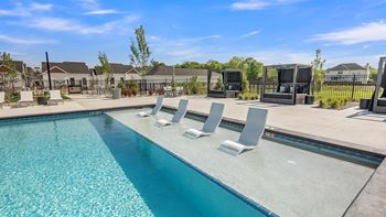 A swimming pool with lounge chairs and a clear blue sky.