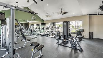 A spacious gym with a variety of equipment and a ceiling fan.