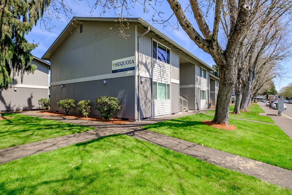 a building with a sidewalk and trees in front of it