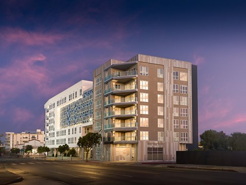 A modern apartment building with balconies and a street in front.