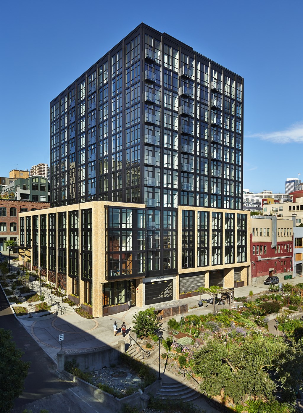 a tall building with many windows and a landscaped area in front of it