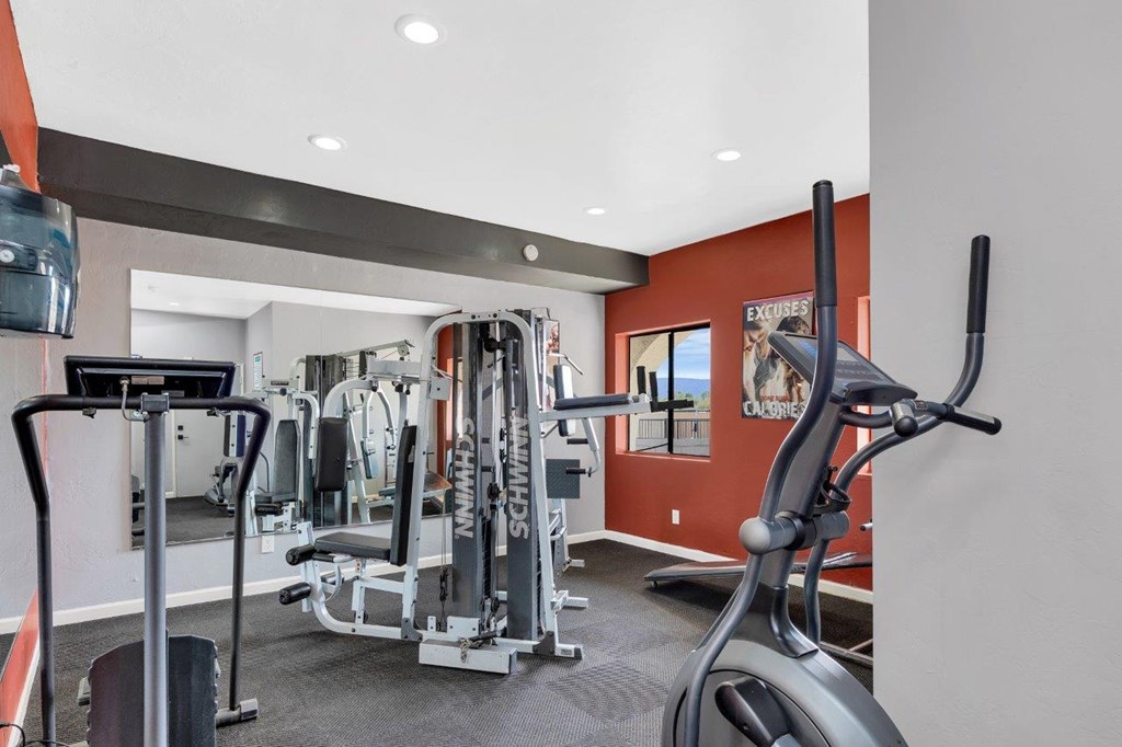 A gym with a variety of equipment including a treadmill, weights, and a bench press.