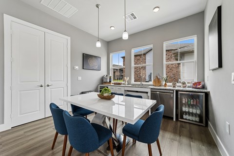 A dining room with a white table and blue chairs.