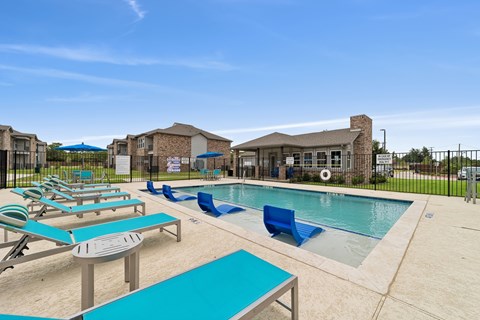 A pool area with sun loungers and a building in the background.