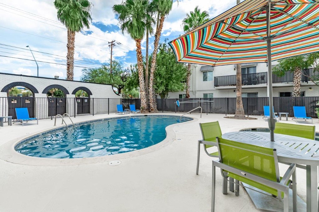 A pool with a table and chairs and a striped umbrella.