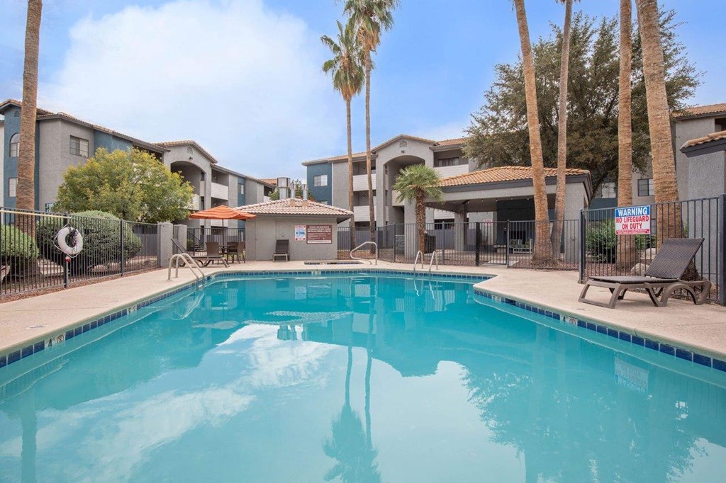 A swimming pool in front of a building with palm trees.