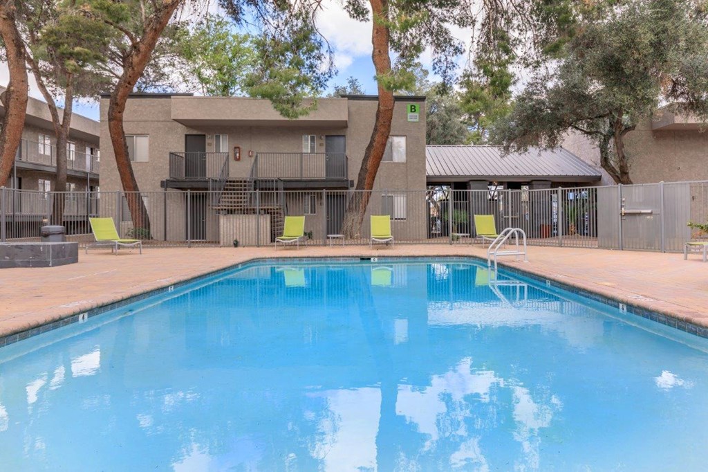 A swimming pool in front of a building surrounded by trees.