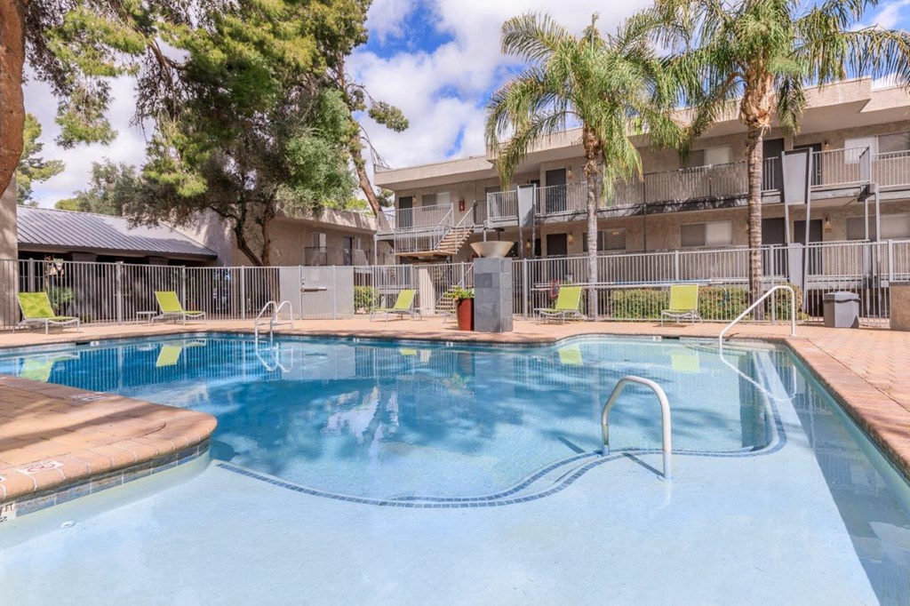 A swimming pool surrounded by palm trees and apartment buildings.
