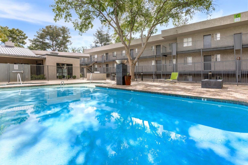 A swimming pool in front of a building with a tree.