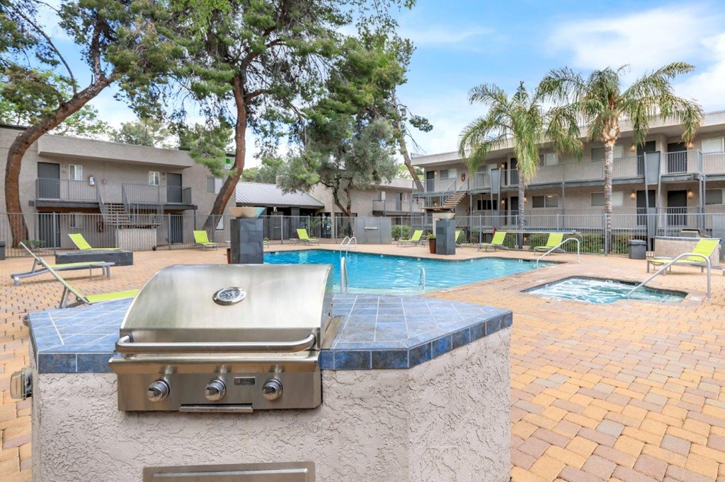 A grill is on a table next to a pool.