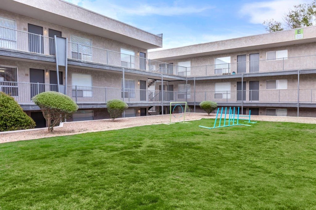 A playground with a slide is in the courtyard of apartment buildings.