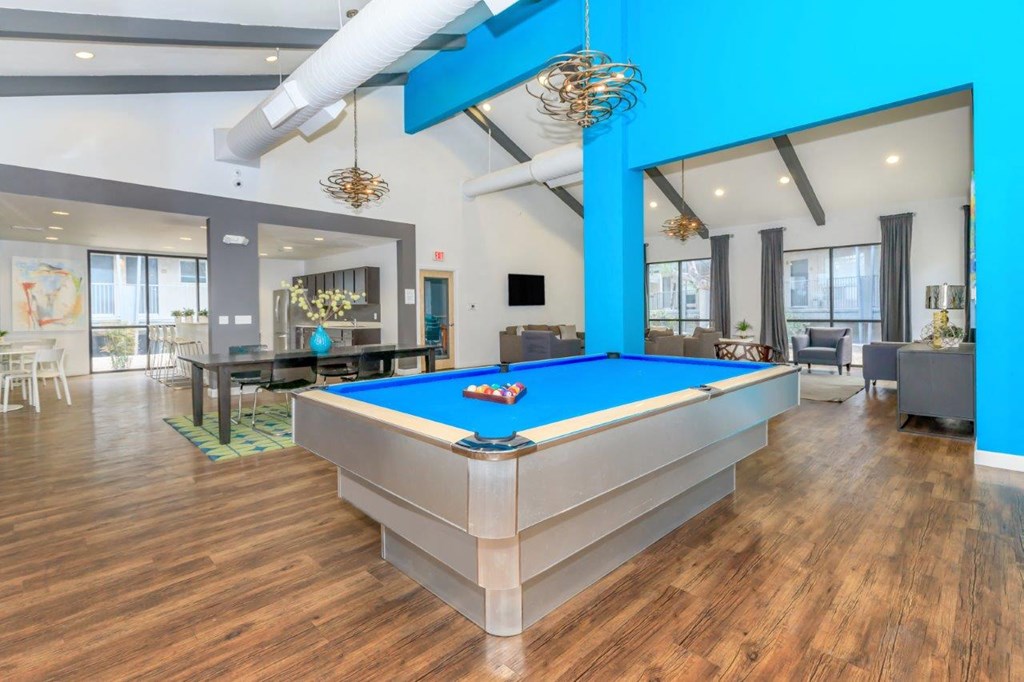 A pool table is in the middle of a room with wood floors.