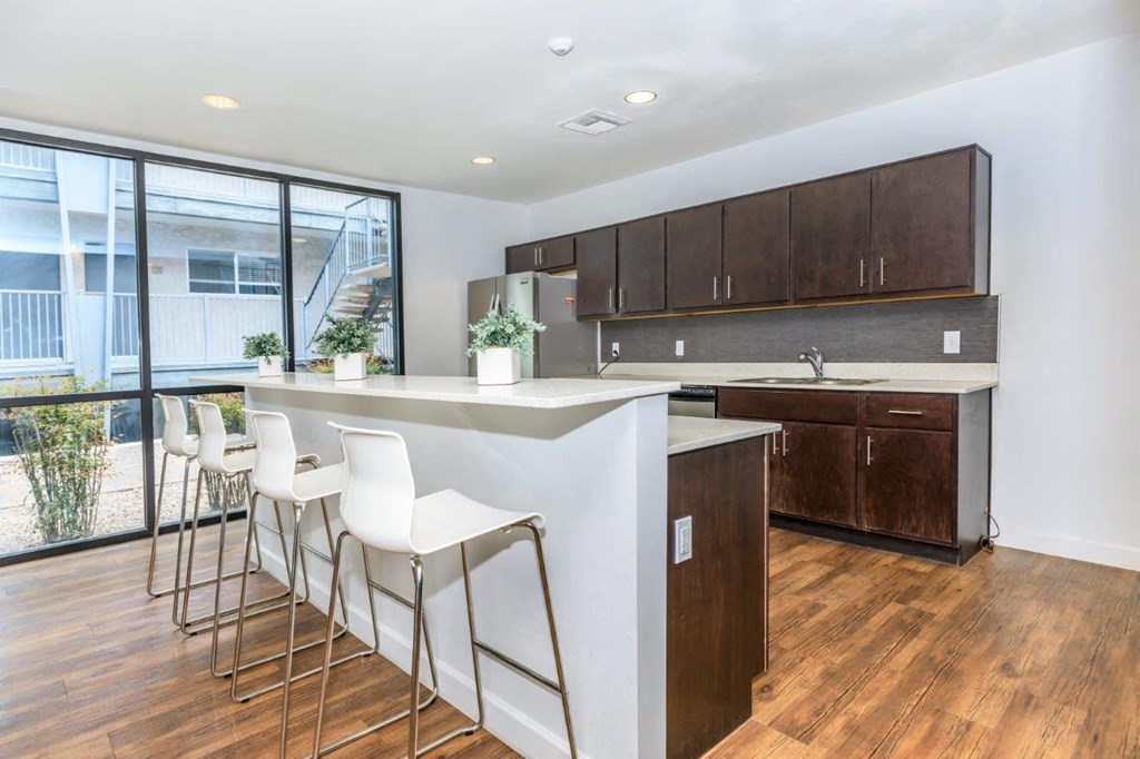 A kitchen with white chairs and brown cabinets.