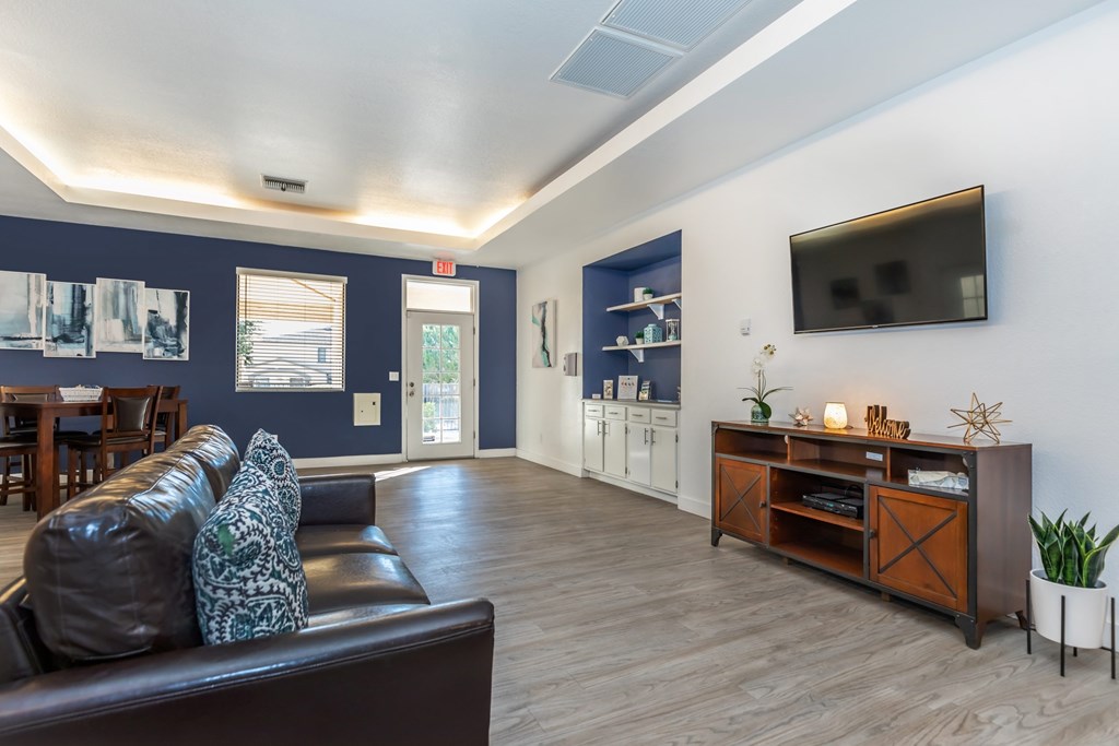 A living room with a brown leather couch and a wooden entertainment center.