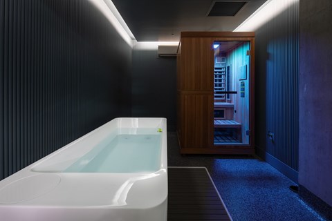 A white bathtub is in a room with a wooden cabinet.