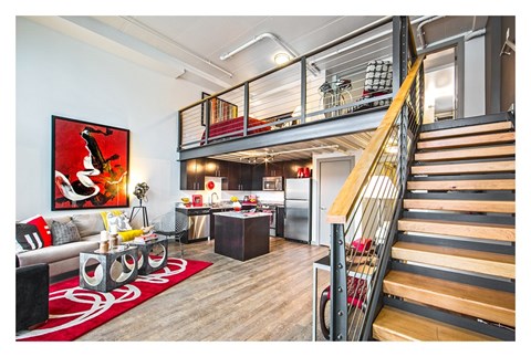 A living room with a red rug and a painting on the wall.