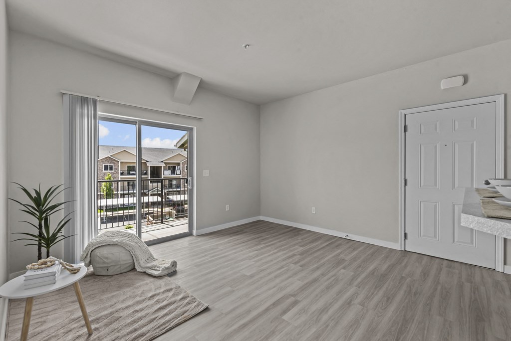 an empty living room with a sliding glass door to a balcony