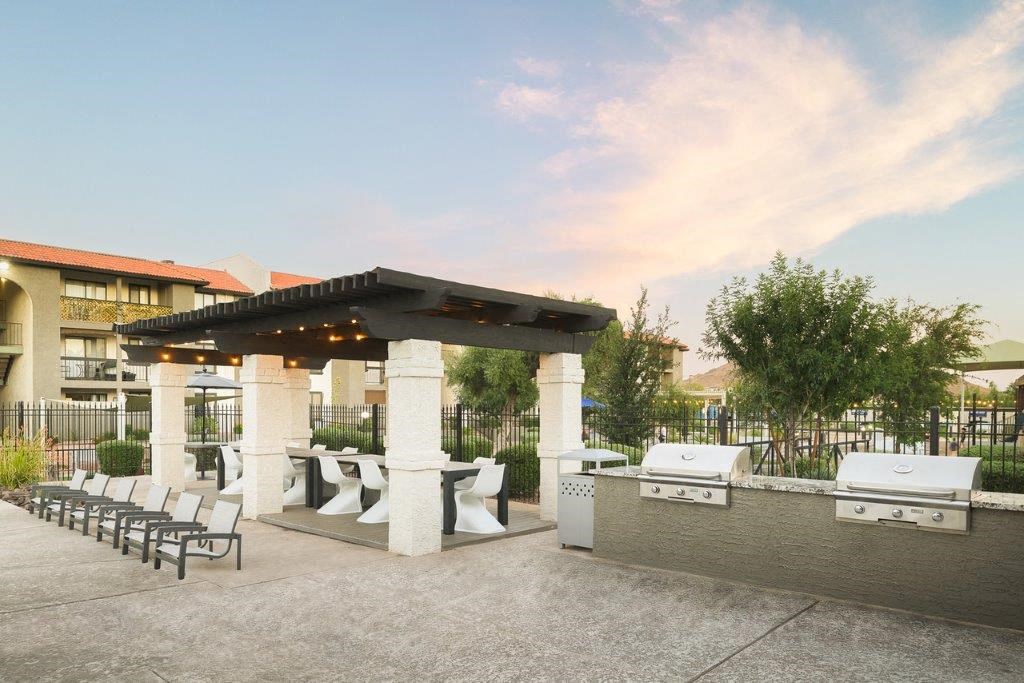 a patio with a grill and tables and chairs