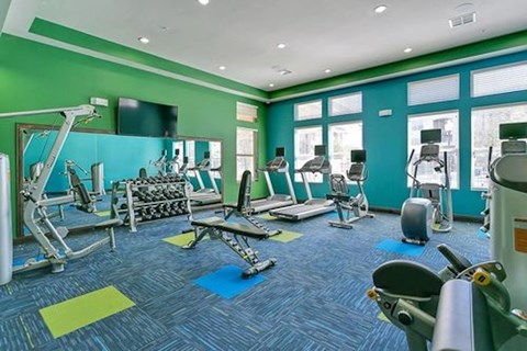 A gym with a variety of equipment including treadmills, weights, and exercise machines.