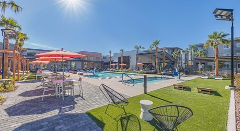 A sunny day at the poolside with palm trees and a red umbrella.