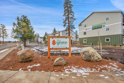 A sign for "the grove" is in front of a building.