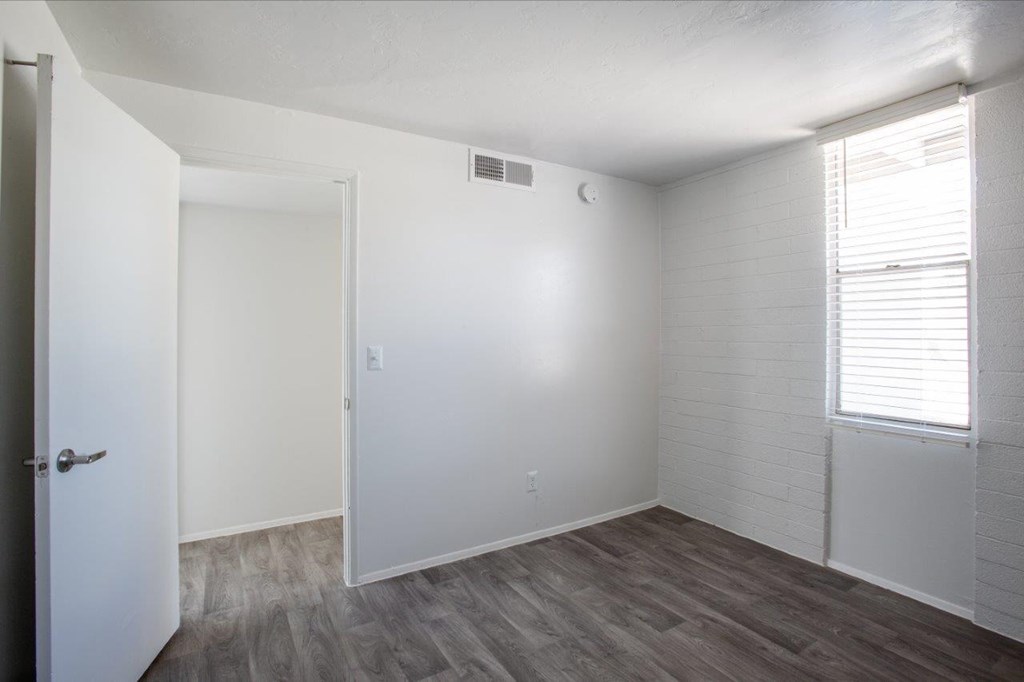A room with a white door and a window with blinds.